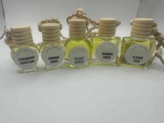 All natural car air fresheners in glass bottles with wooden lids and hanging cords, available in various scents.