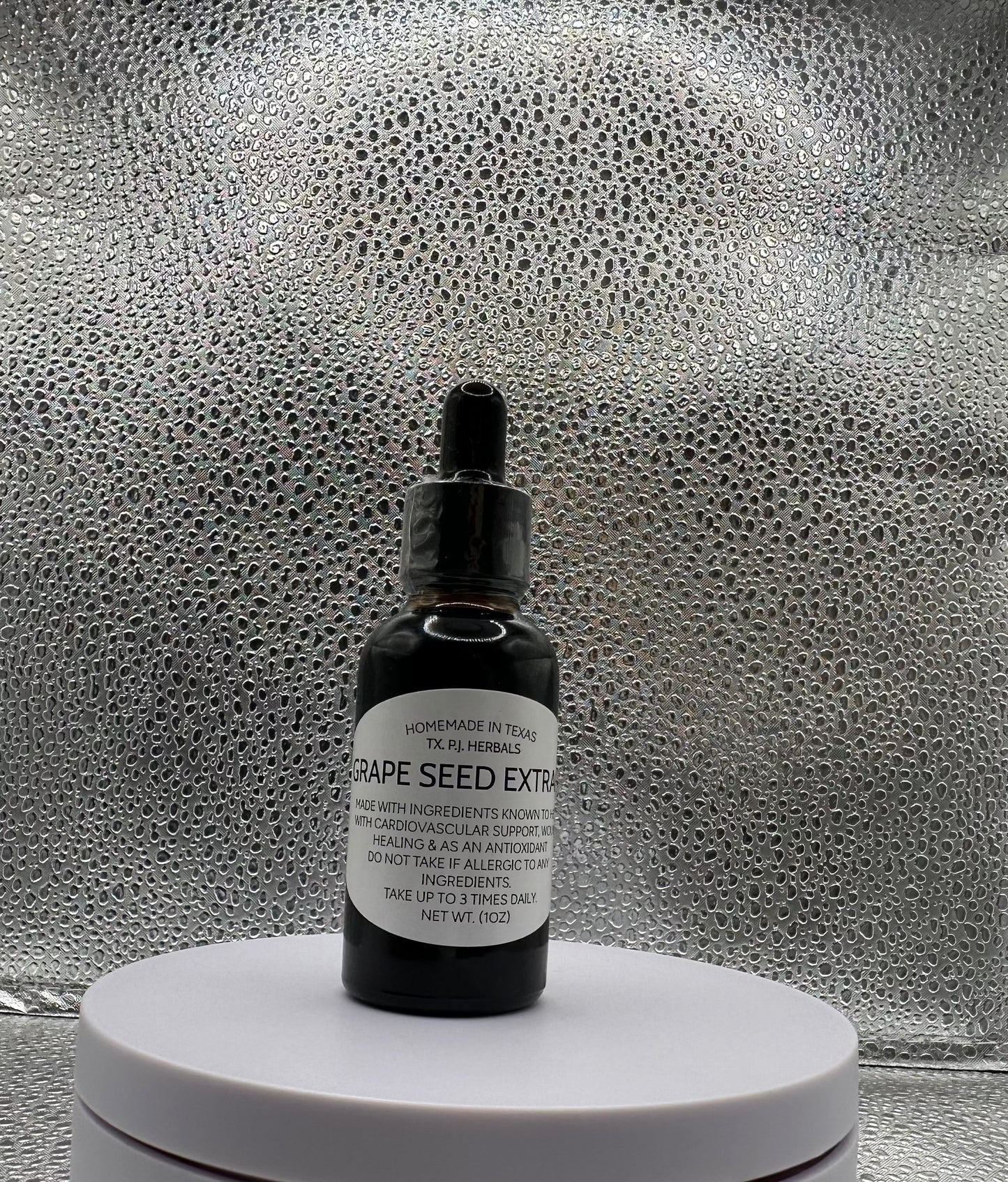 Bottle of all-natural grape seed tincture with fresh grapes and leaves